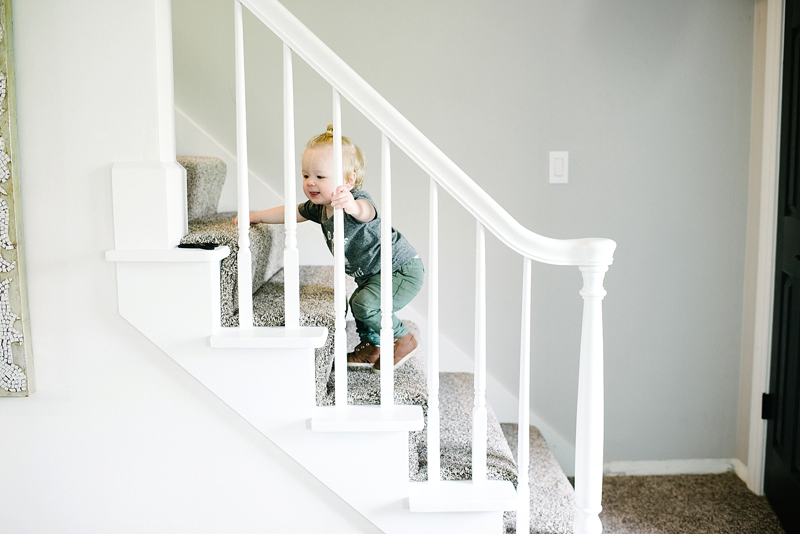 toddler boy wearing man bun walking up staircase 