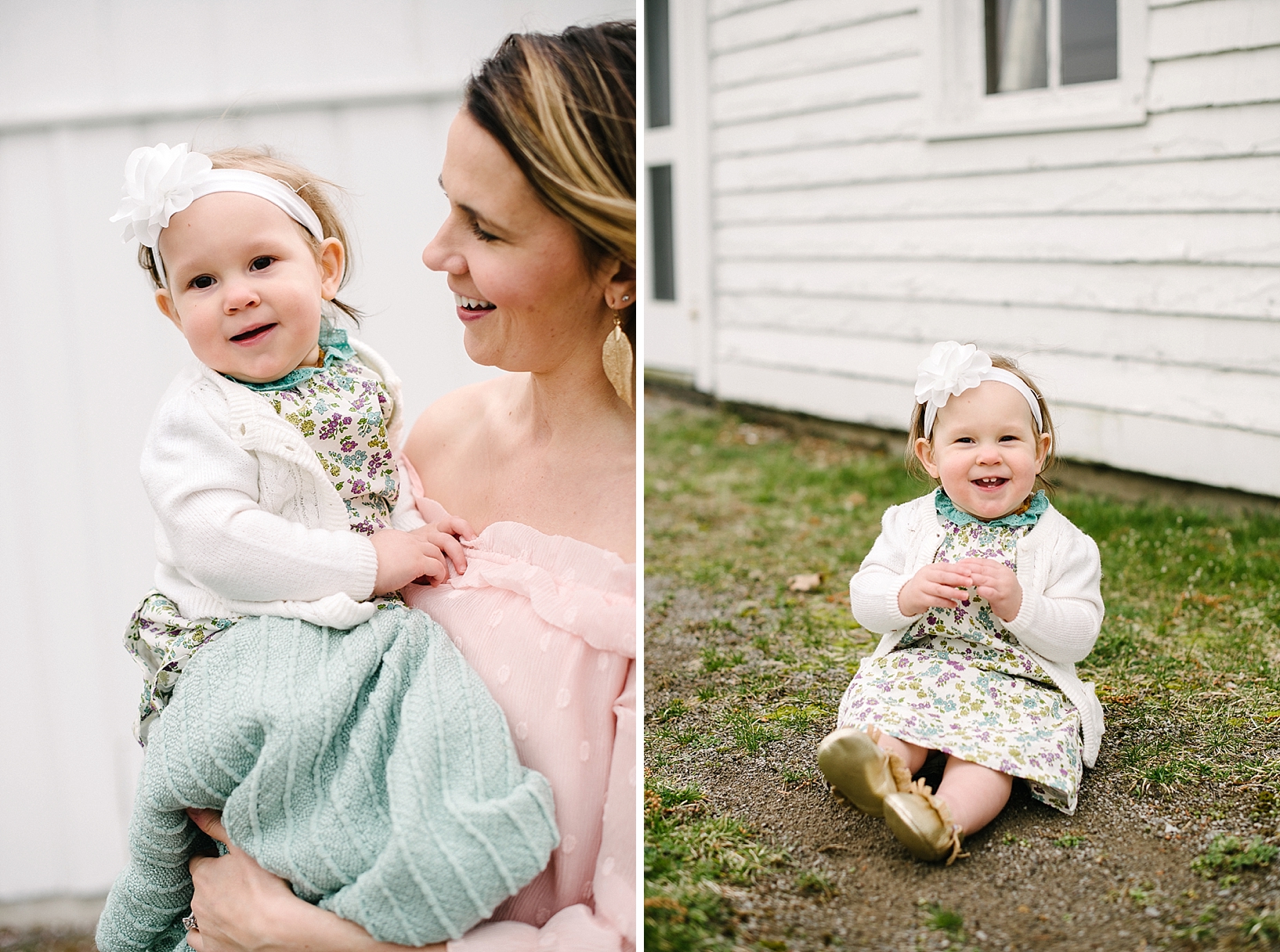 one year old girl wearing floral print dress and cream cardigan sitting in front of white rustic farmhouse