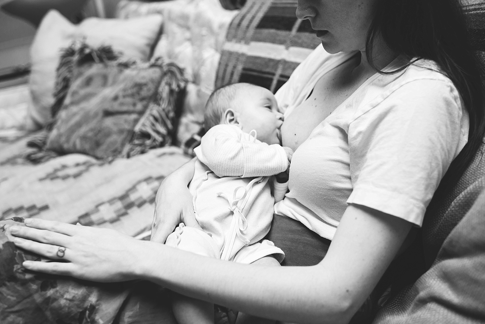 mother breastfeeding baby sitting on couch