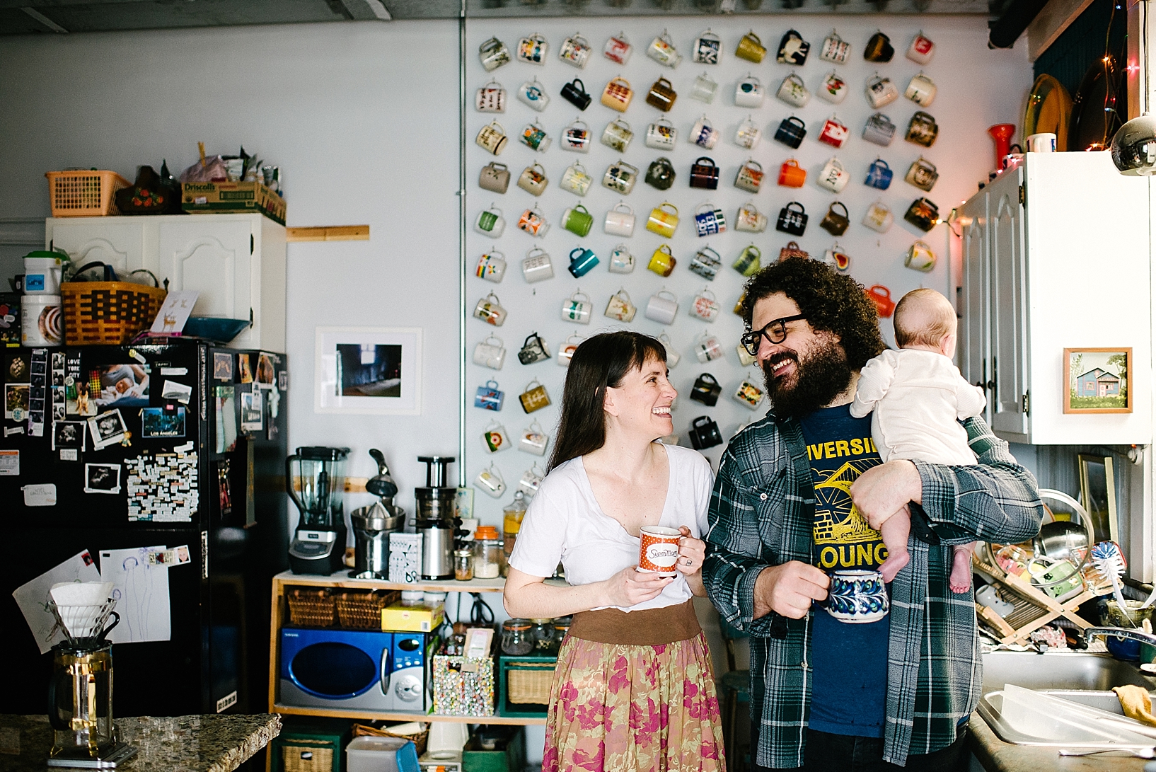 bohemian couple standing in kitchen holding coffee cups smiling at each other