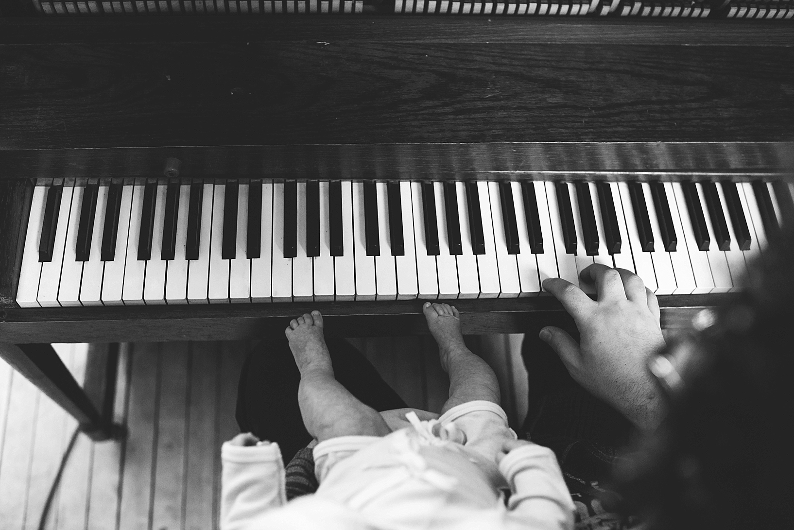 man playing piano with baby in his lap
