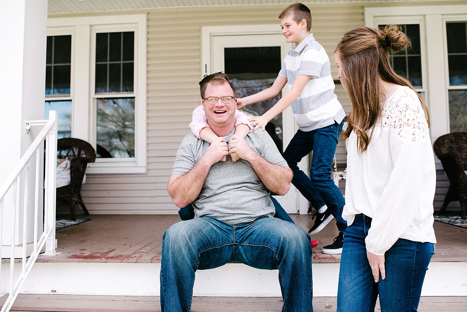 dad wrestling with kids on front porch of house