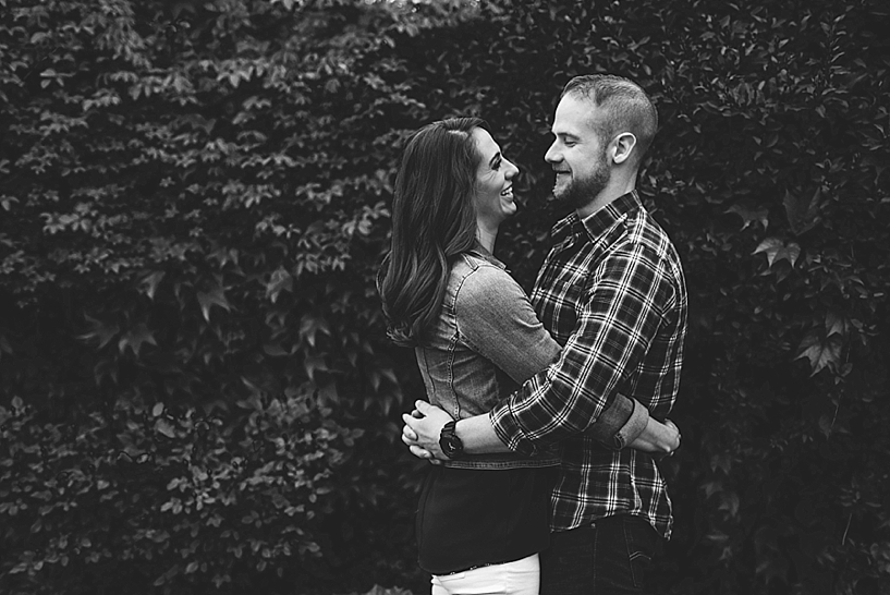 man and woman hugging in front of ivy wall