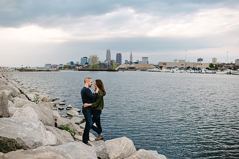 couple standing on rocks hugging with Cleveland city skyline in the background