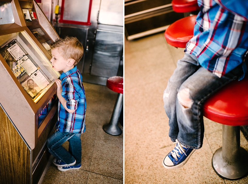 young boy wearing blue converse and blue and red plaid shirt picking songs at retro juke box