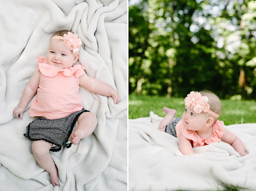 6 month old girl wearing coral shirt with headband laying on blanket in backyard