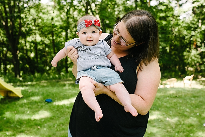 mom holding 6 month old daughter in her arms in backyard
