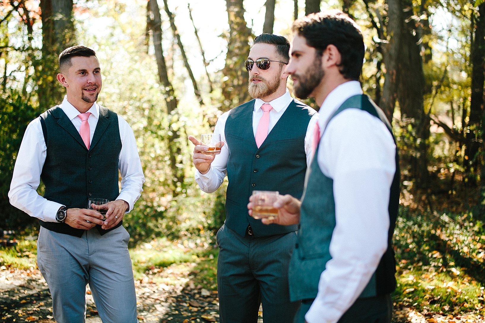 groom and groomsmen wearing gray suits drinking whiskey outside