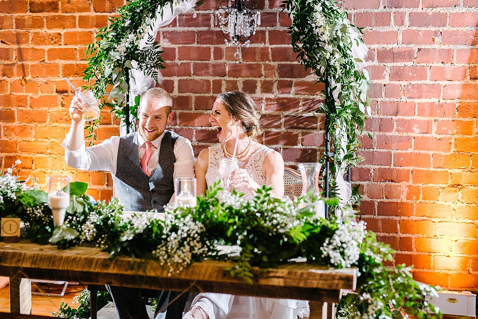 bride and groom sitting at sweetheart table at wedding reception