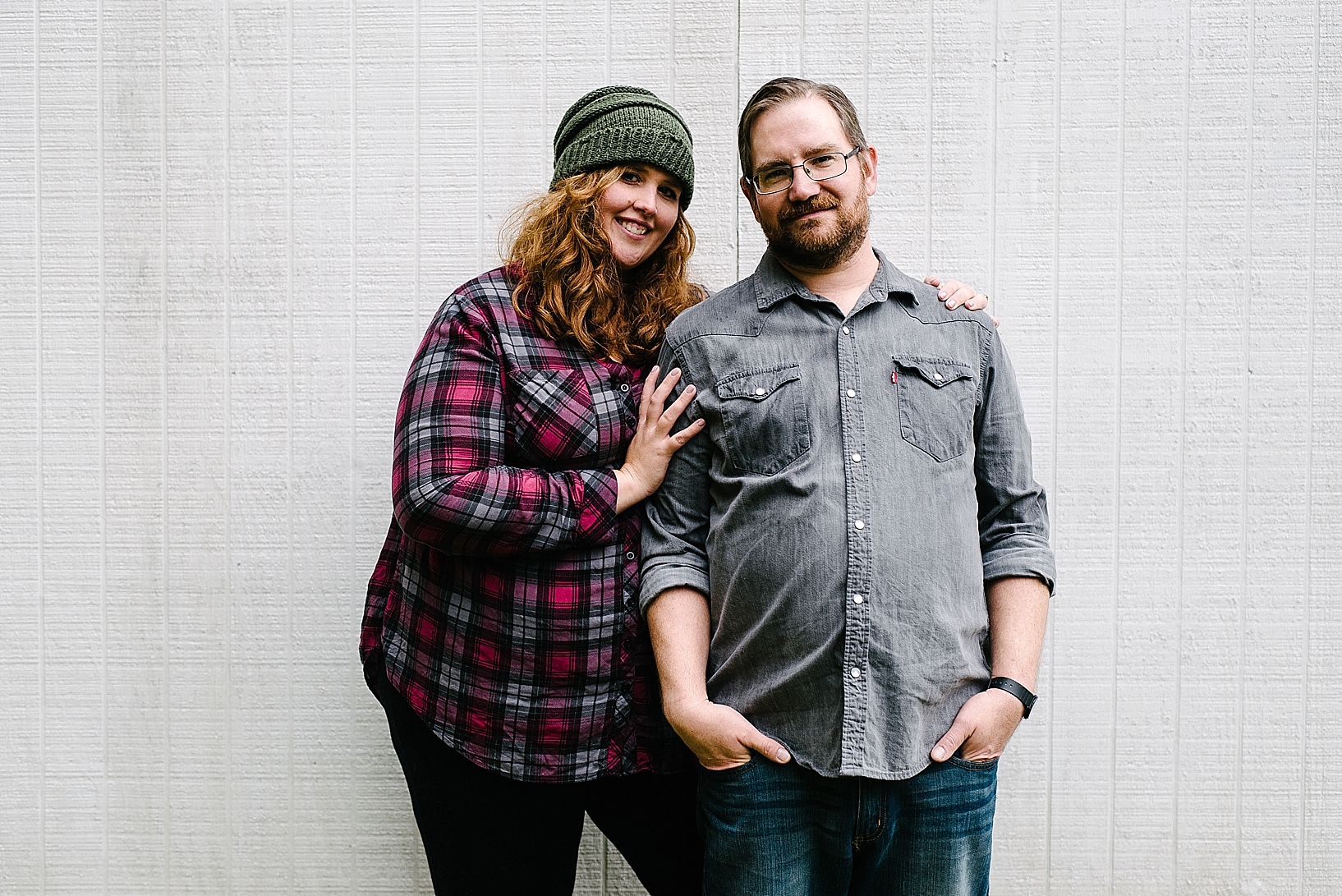woman wearing flannel and knit hat standing with man wearing button down and jeans