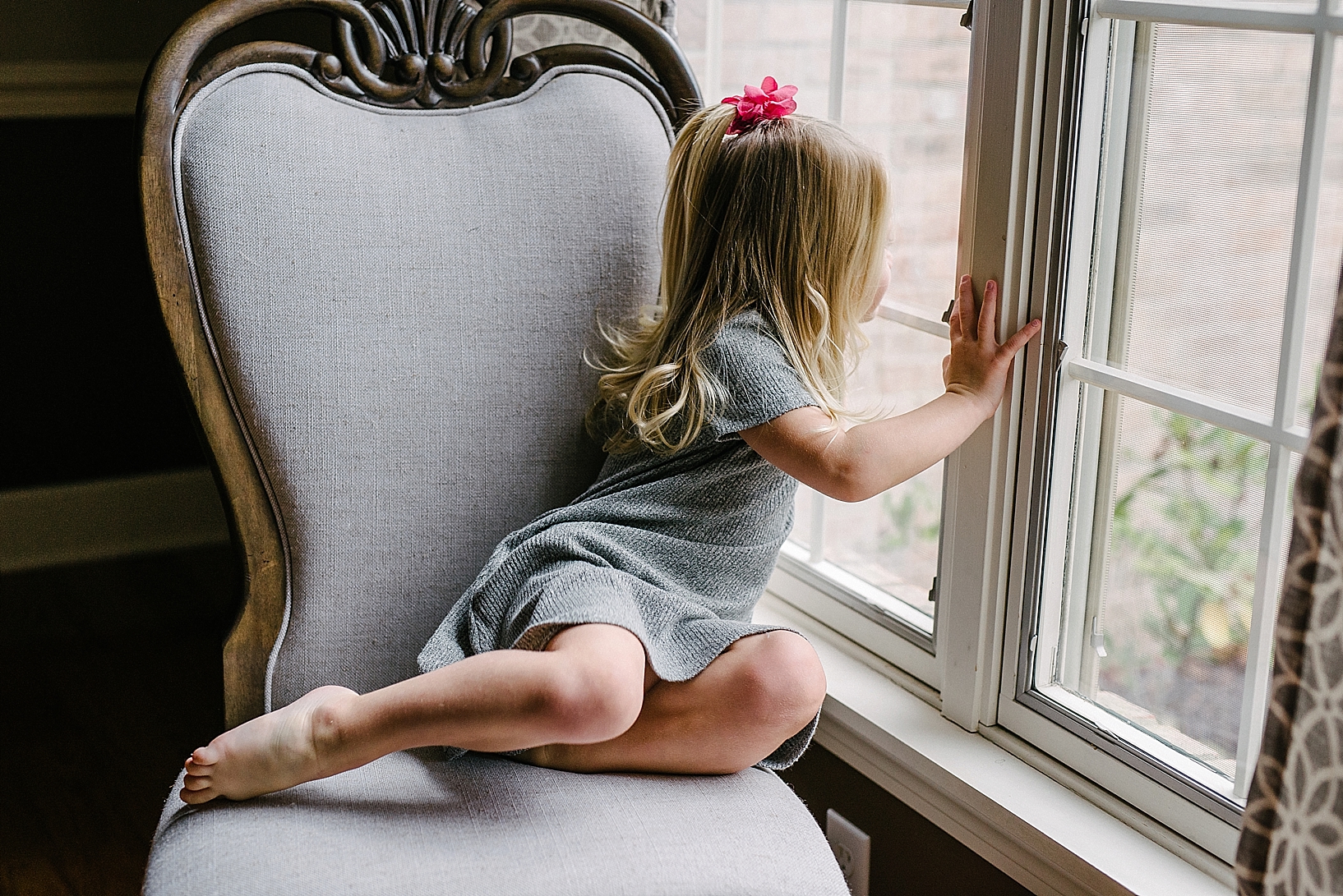 little girl sitting in chair looking out window