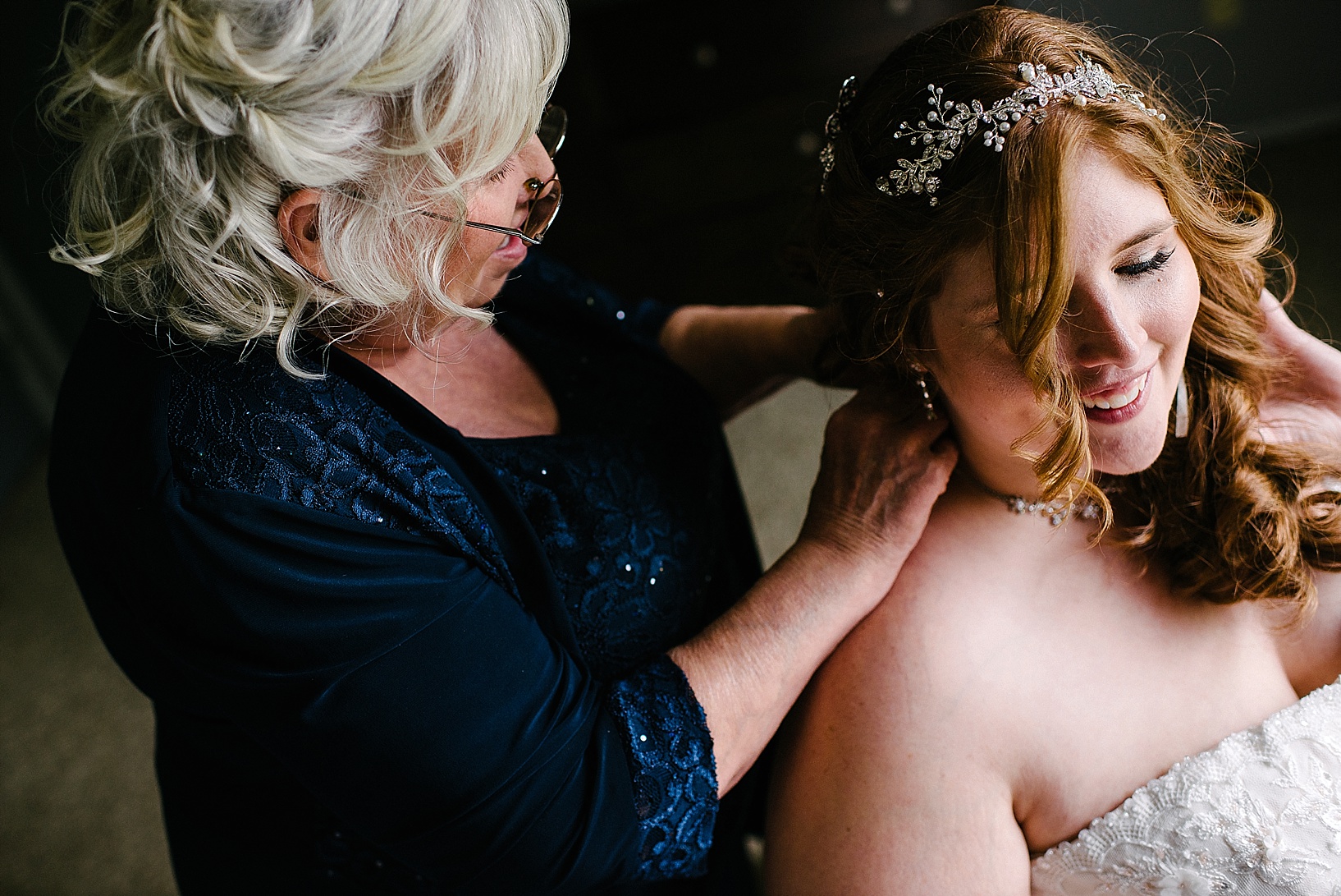 mother helping bride put on necklace