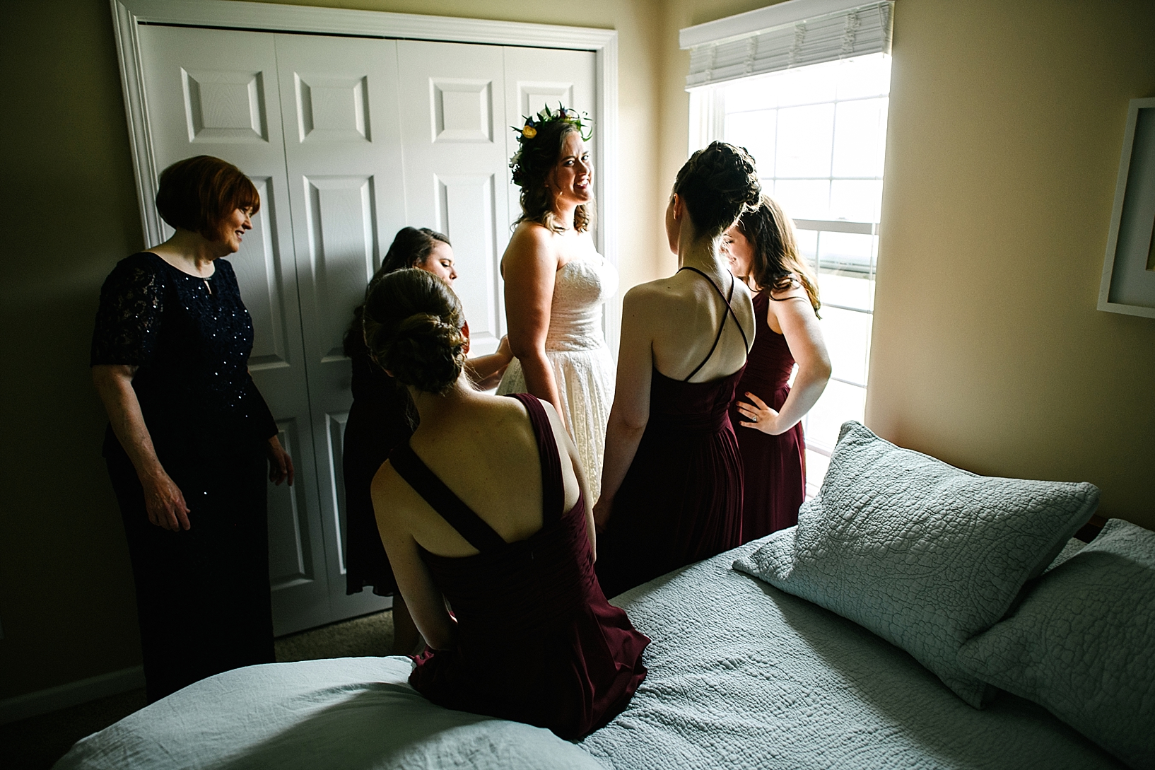 bridesmaids helping bride into her gown