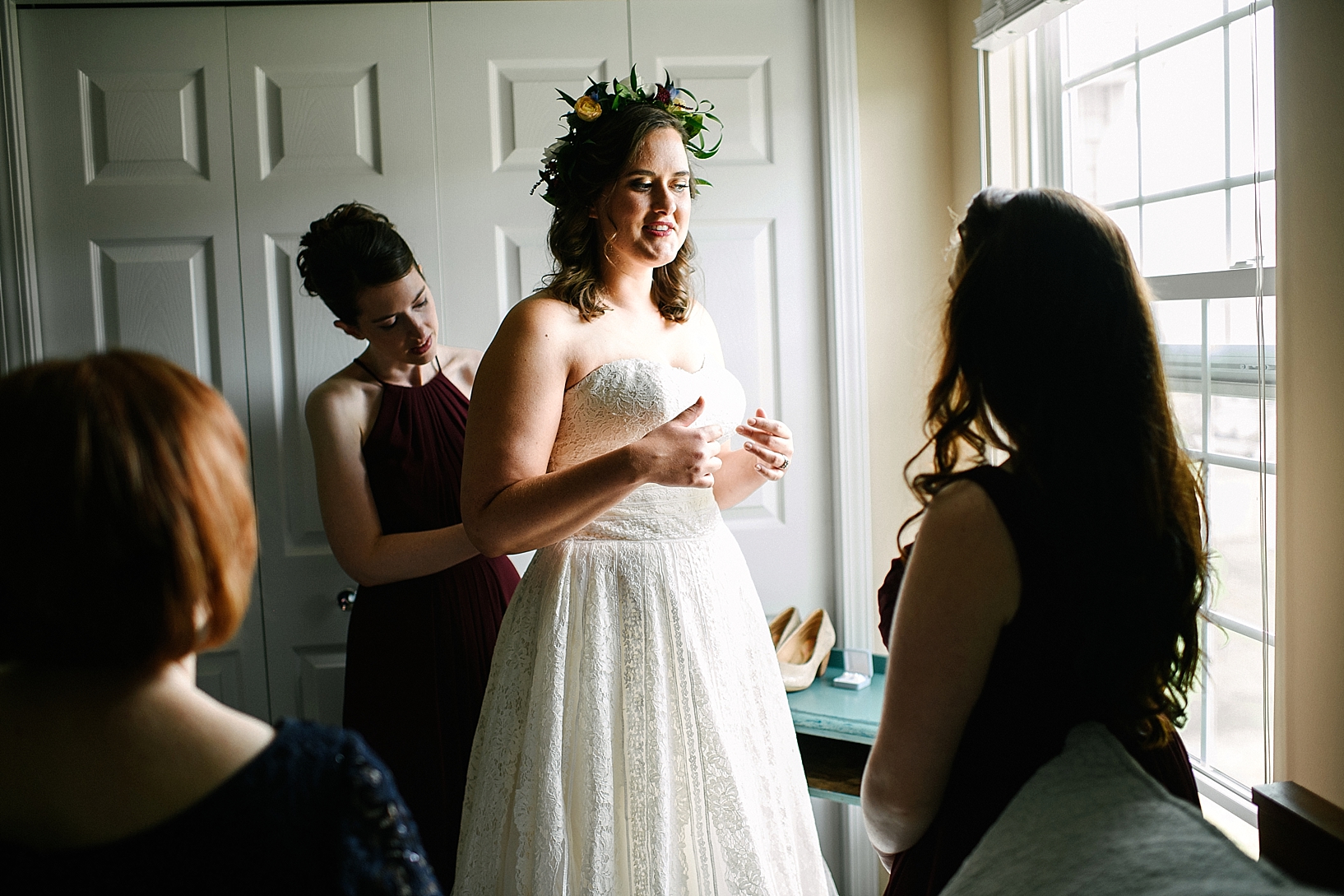 bridesmaids helping bride into her gown