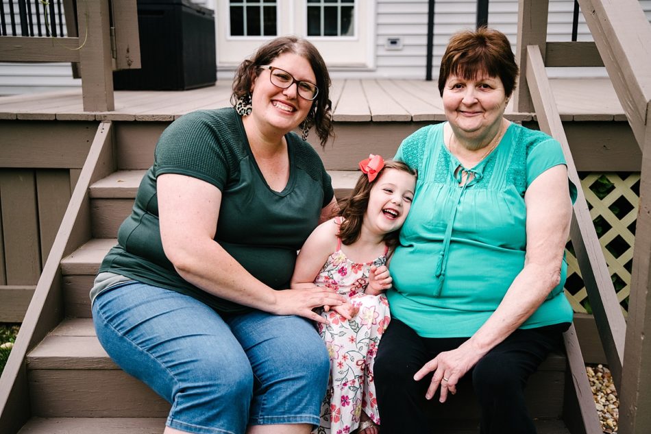 Grandma, mom, and daughter sit on porch steps in generation family session