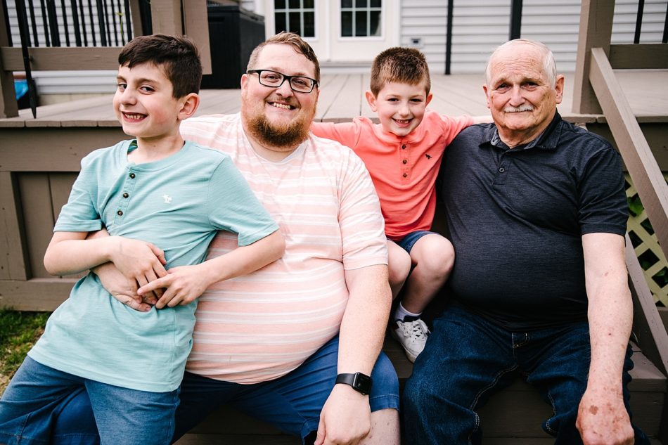 Grandpa, dad, and sons sit on porch steps in generation family session
