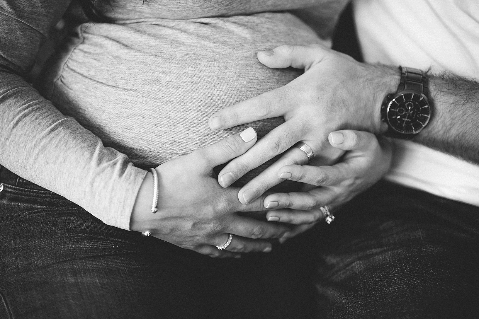 Husband and pregnant wife hold their hands on pregnant belly maternity photography