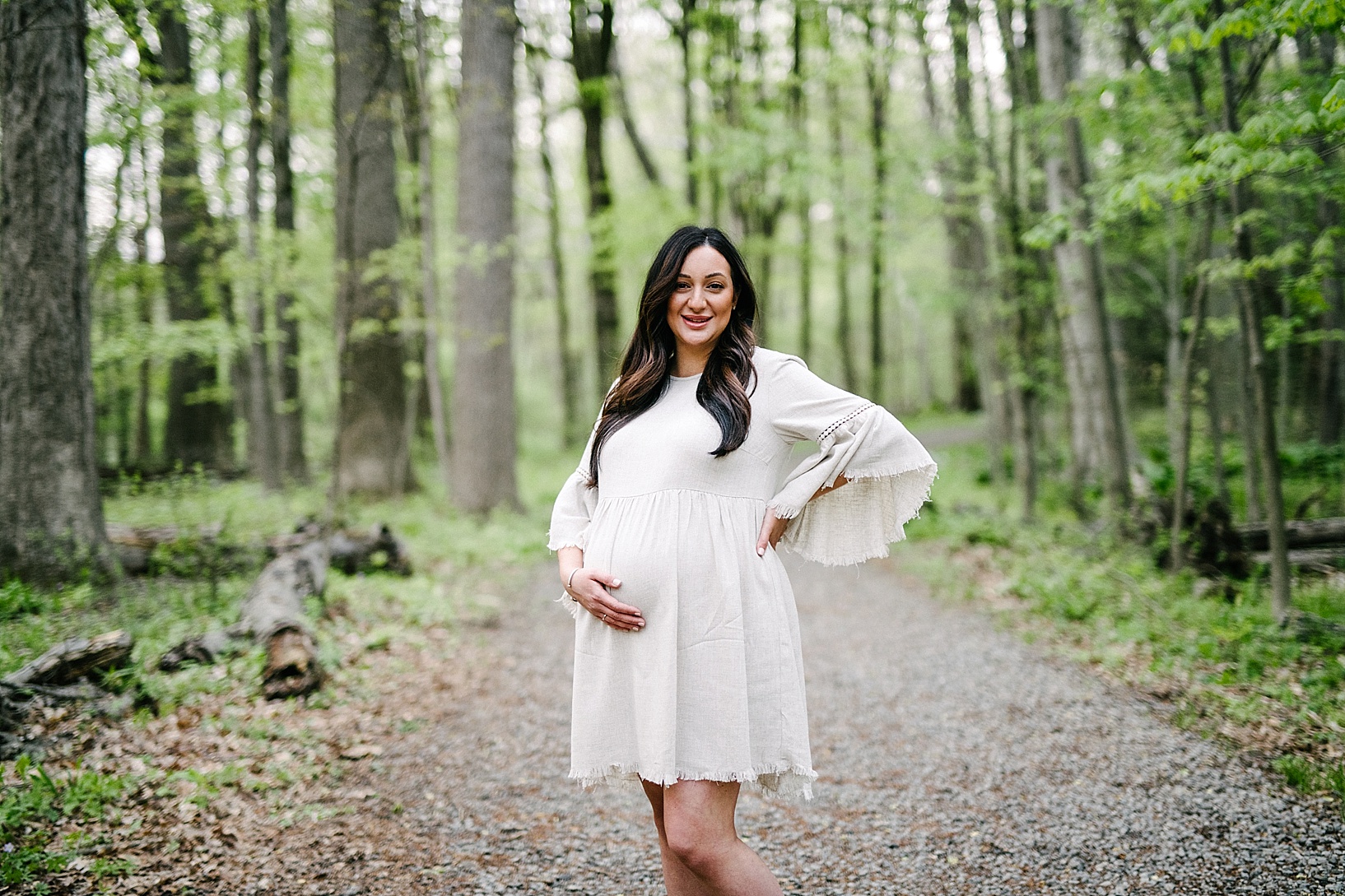 Pregnant woman holds belly in woods maternity photography