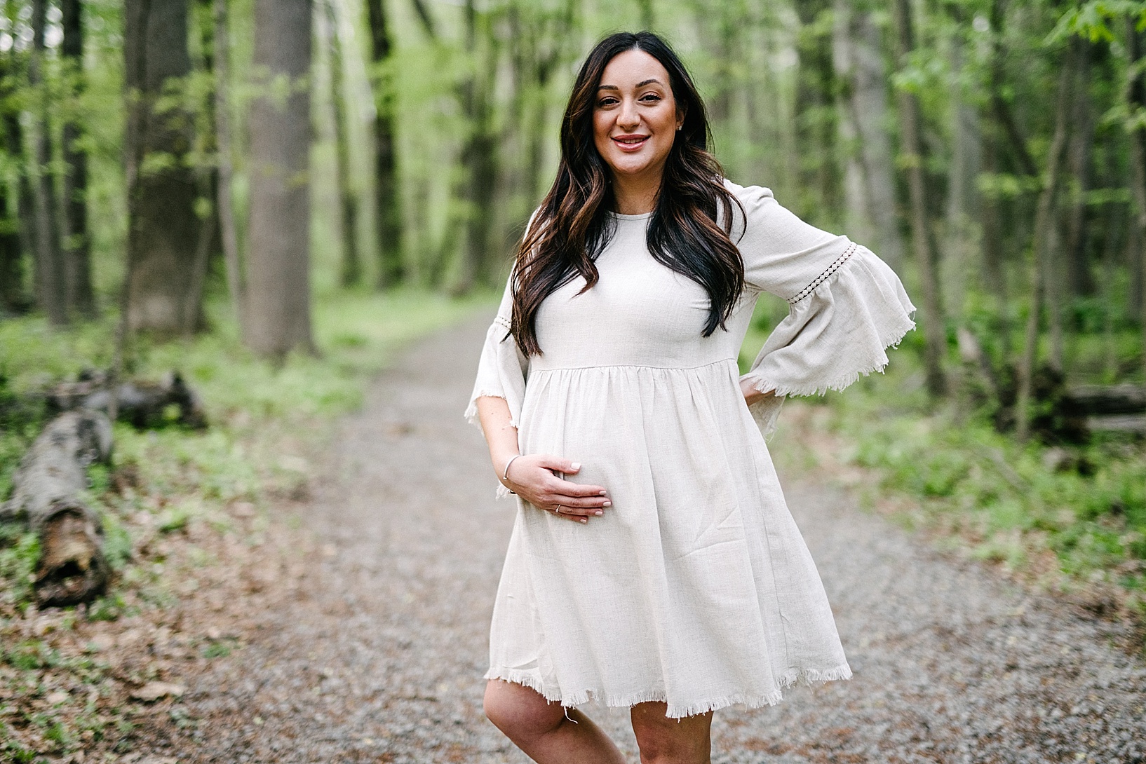 Soon-to-be mom holds baby bump in woods maternity photography