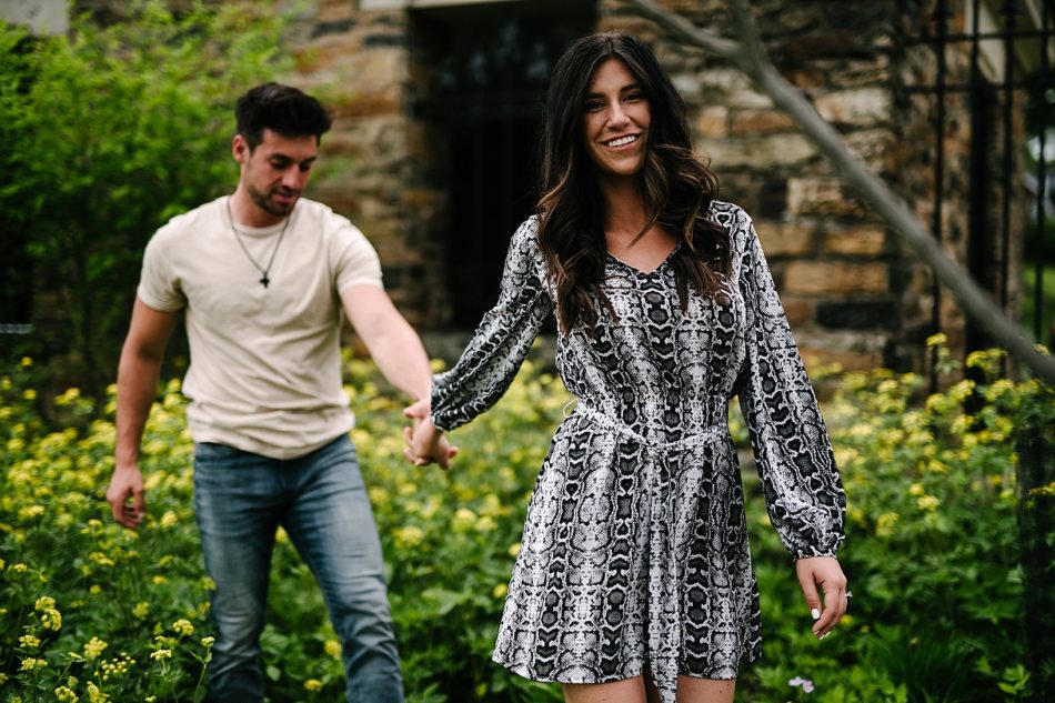 Woman holds fiance's hand while walking towards camera in surprise proposal