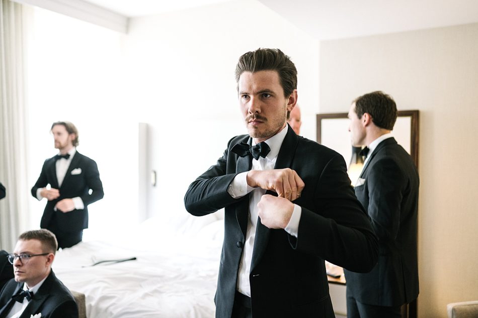 Groom puts in pocket square while getting ready for wedding ceremony