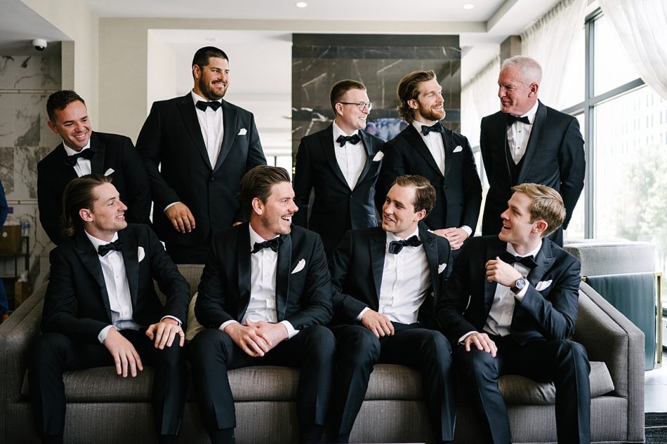 Groom and groomsmen smile and laugh together