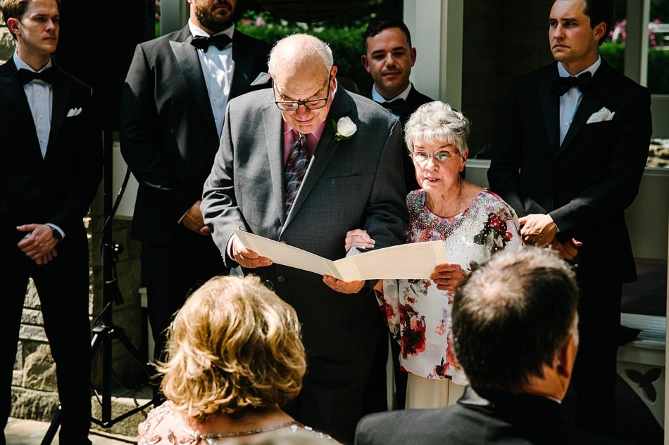 An older couple reads something during wedding ceremony