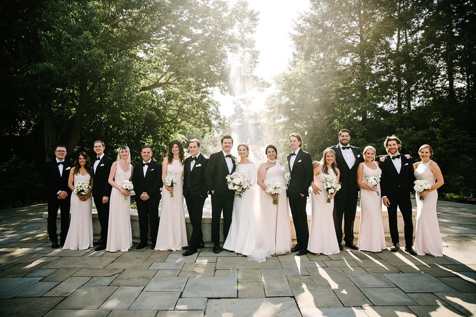 Wedding party poses in front of a fountain in pairs