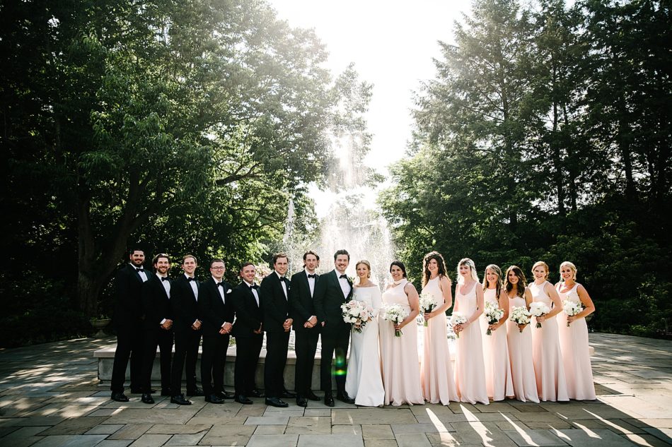 Wedding party poses in a line in front of a fountain
