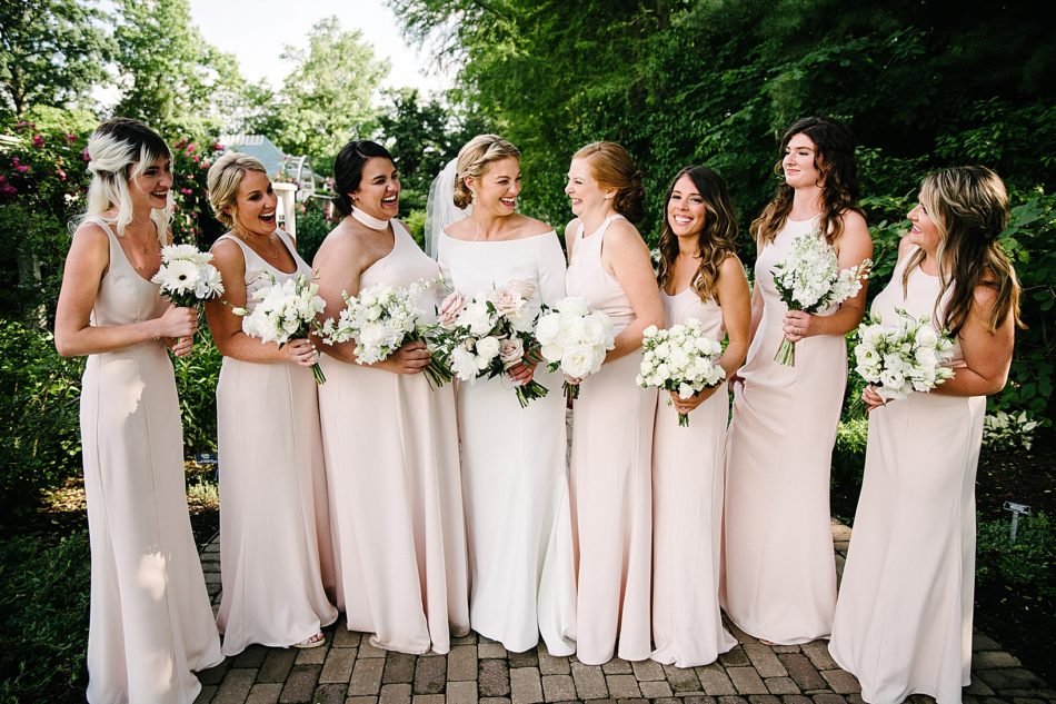 Bride and Bridesmaids post in light pink gowns with white flower bouquets