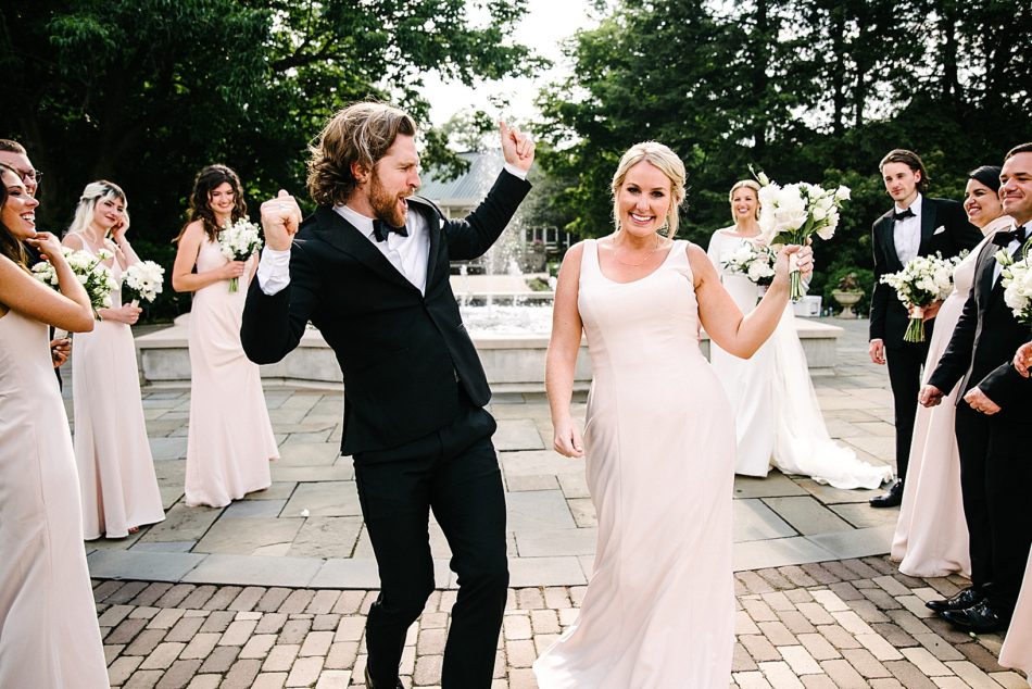 Groomsman and bridesmaid dance in front fountain