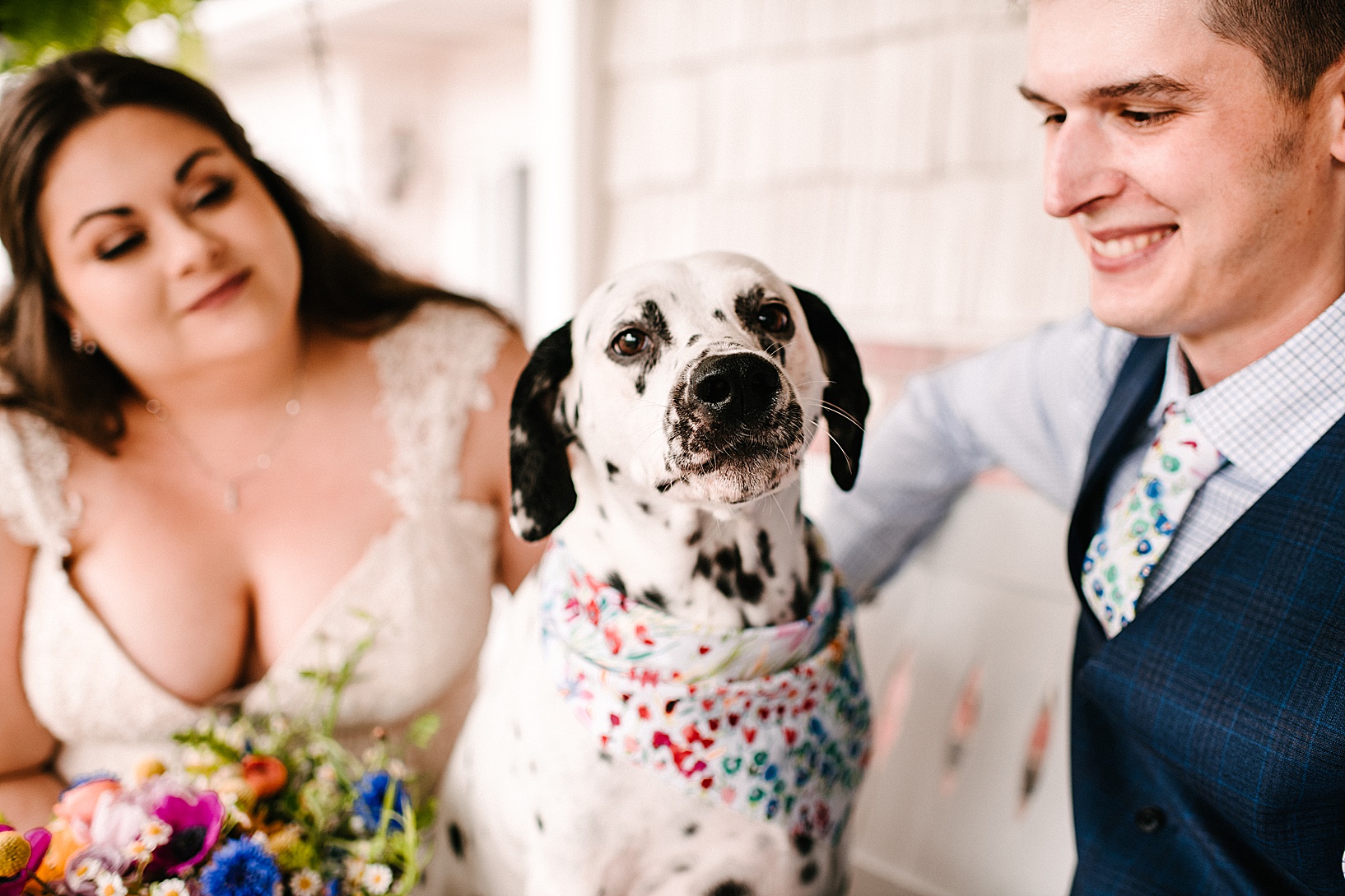 Bride and groom both smiling at their dog on white swing at their new home