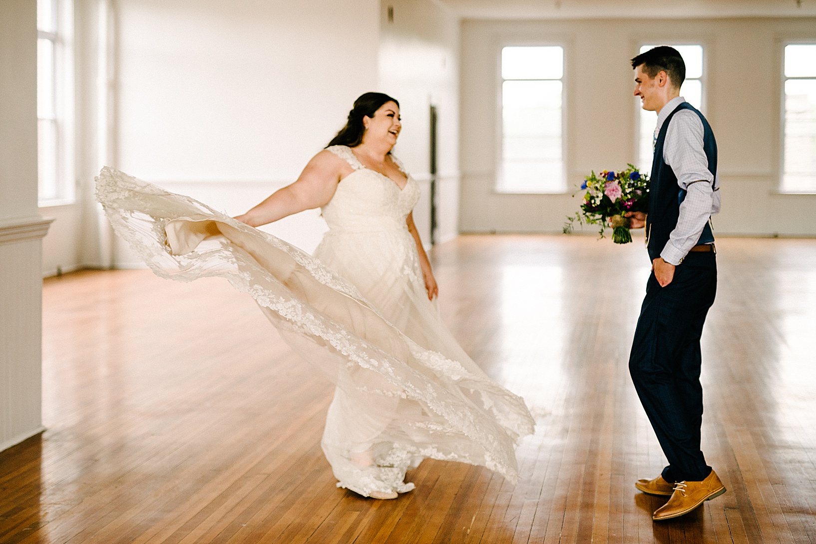 Bride twirls her wedding gown as groom holds her bouquet