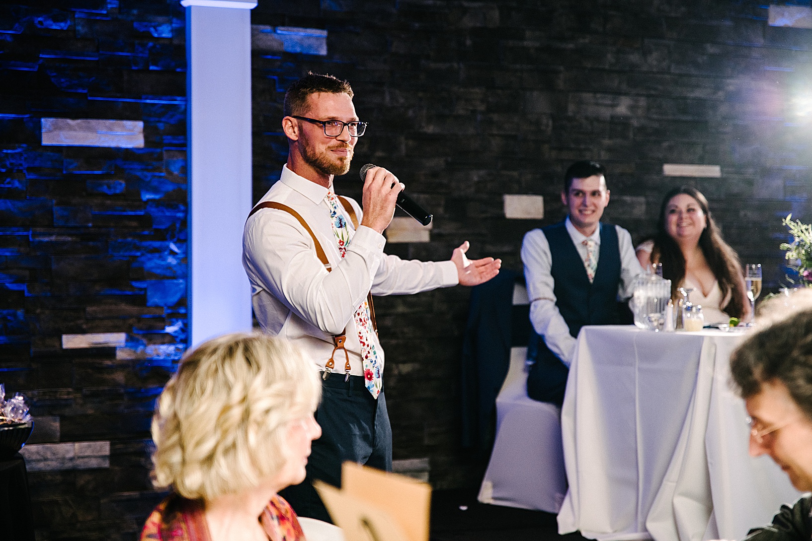 Best man gives his speech while pointing to groom and bride