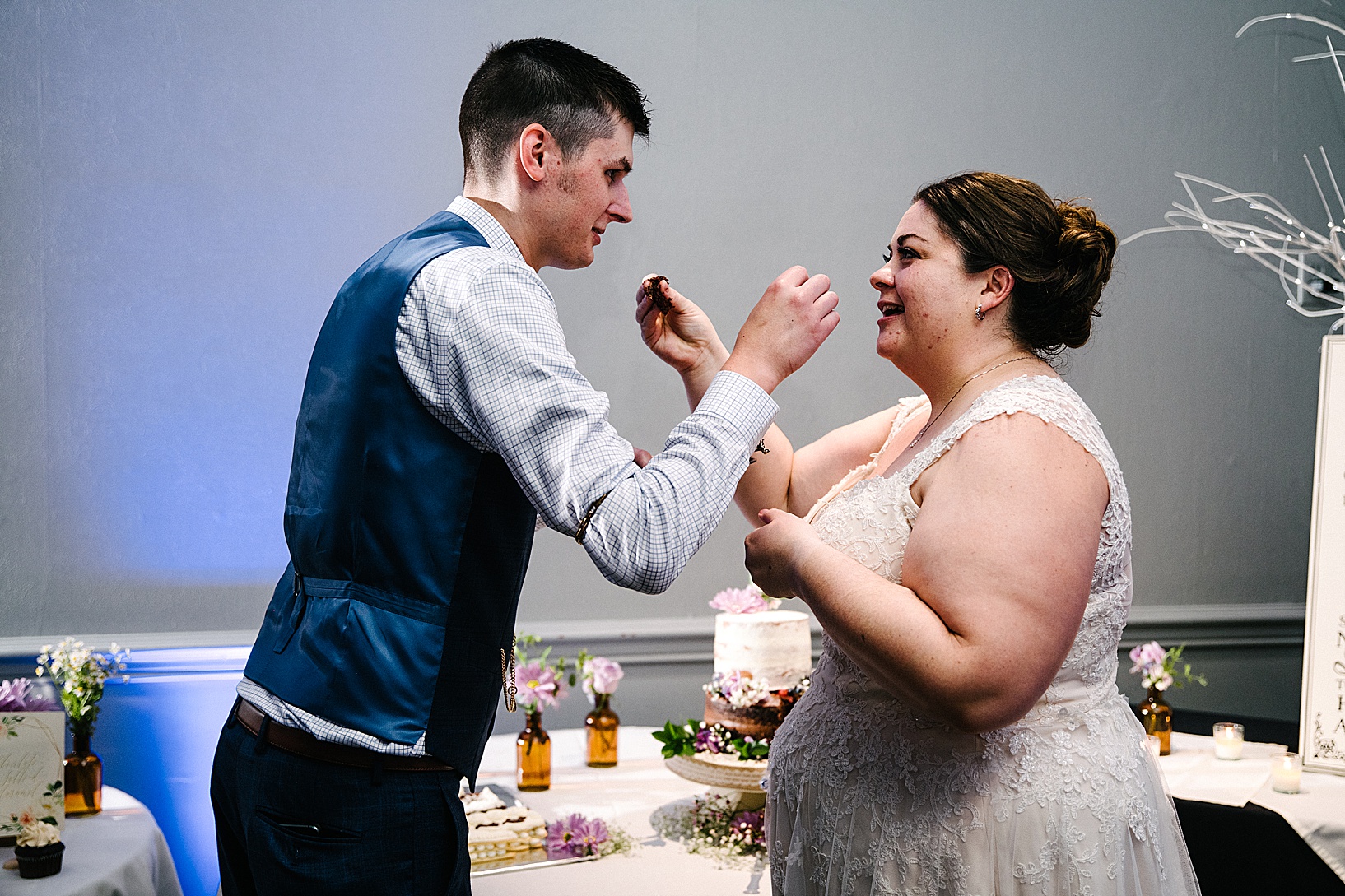 Groom and bride feed each other cake at post wedding celebration