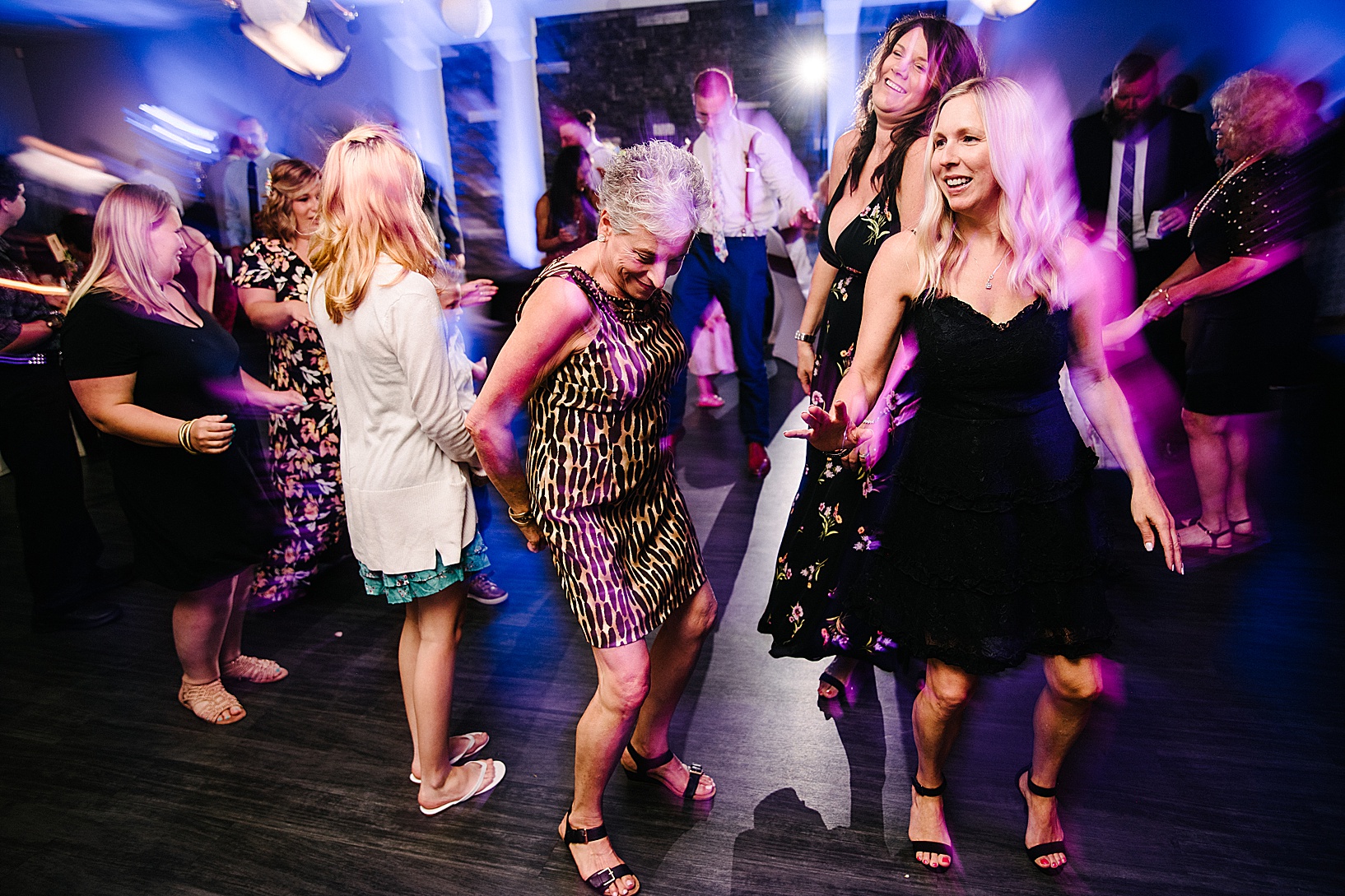 Women standing around laughing on the dance floor and getting ready to dance at post wedding celebration