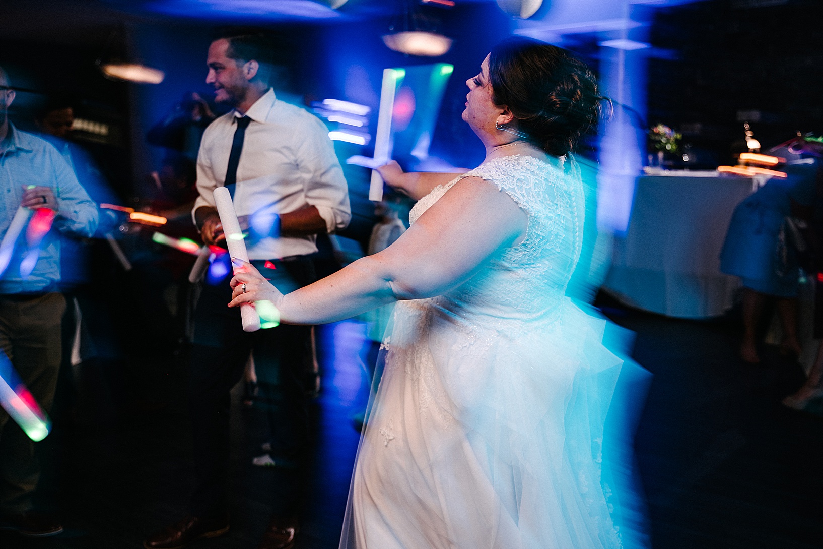 Out of focus image of bride dancing on the dance floor in neon light at post wedding celebration