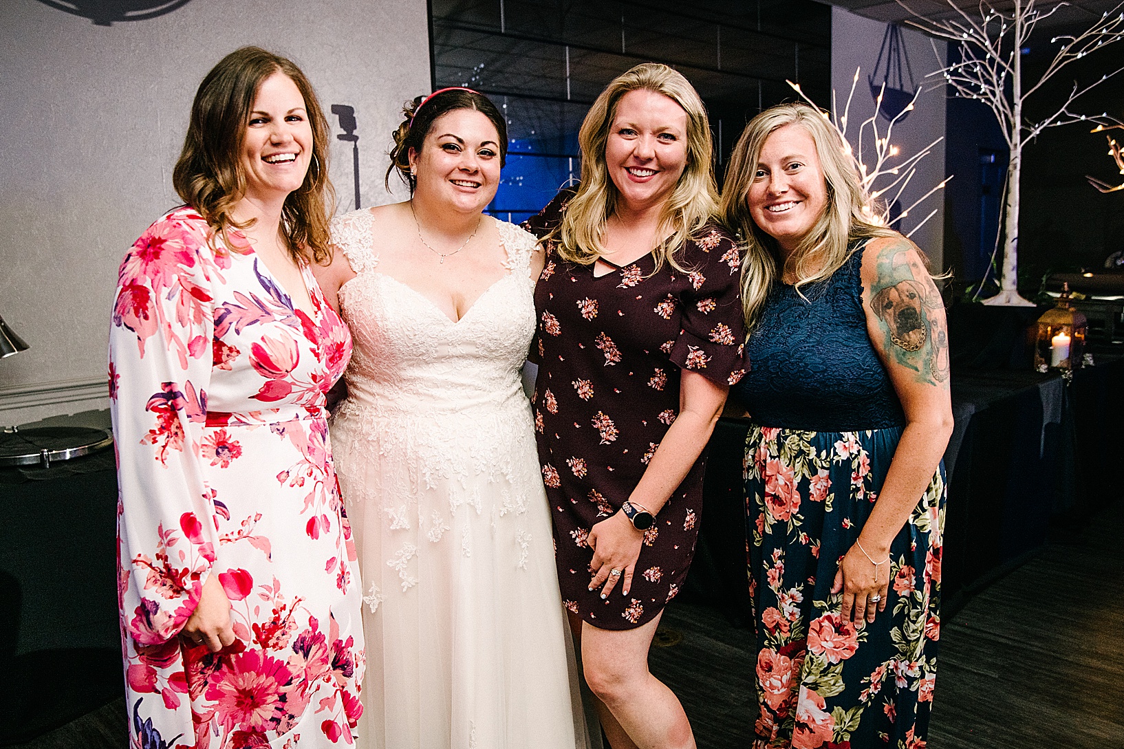 Bride poses and smiles with three ladies at post wedding celebration