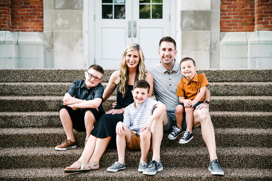 Family of five poses on steps in front of red brick building at Mount Union.
