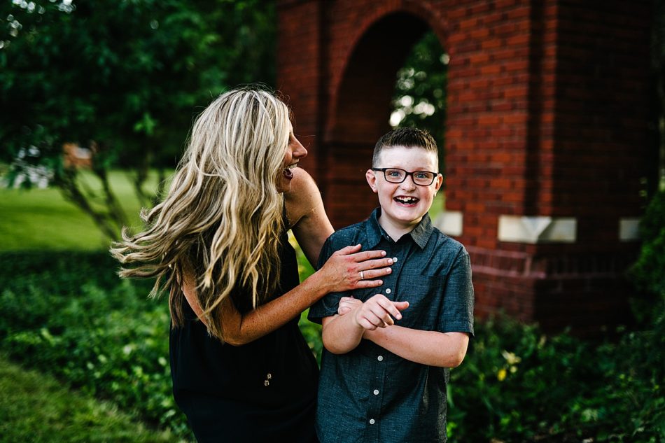 Mom hugs her young son with glasses as they laugh together.