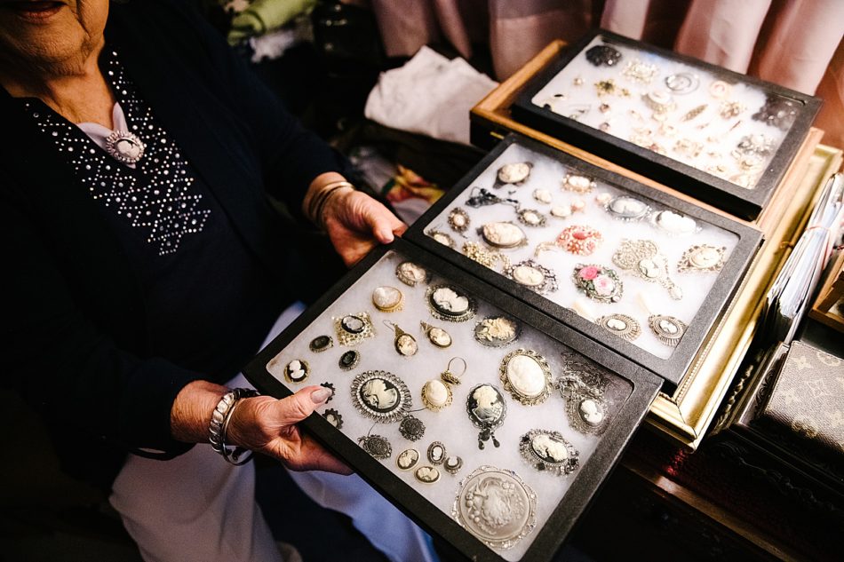 Grandmother shows large collection of antique brooches during legacy portrait session.