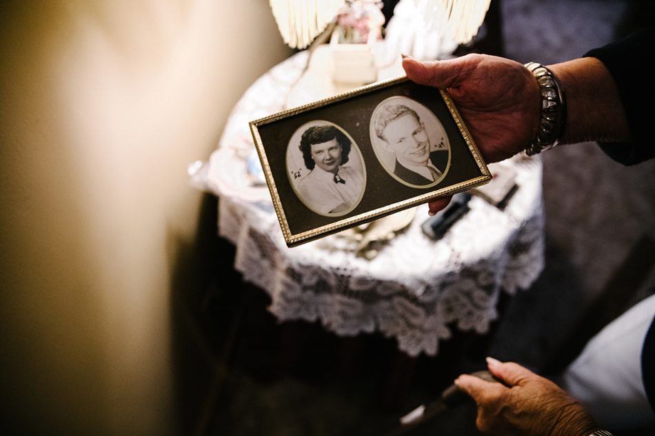 Grandmother holds an antique frame containing her and her husbands portraits.
