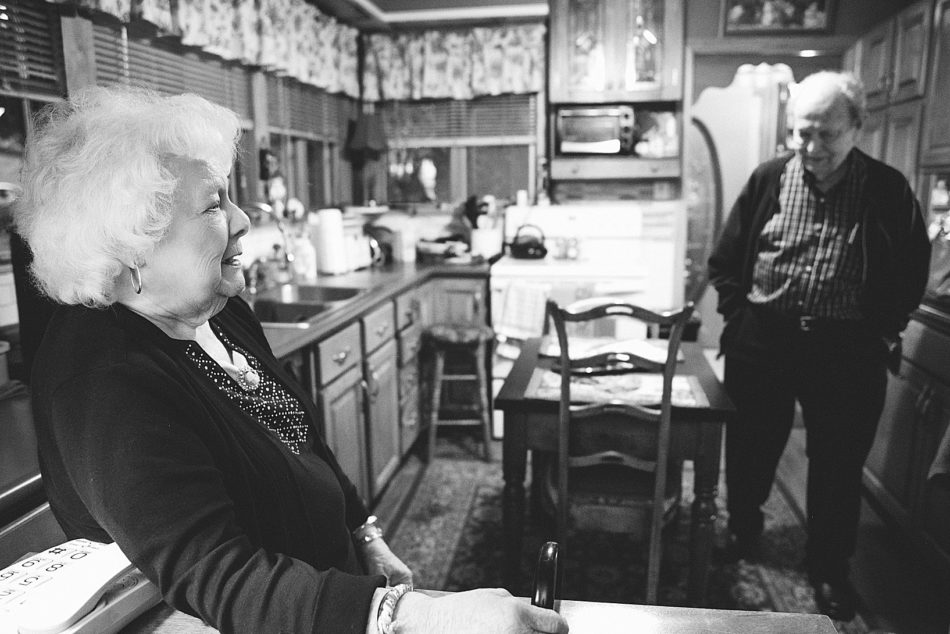 Older woman and man stand talking in their kitchen.