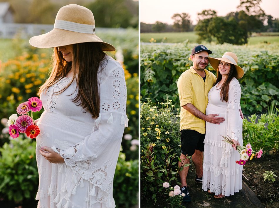 Pregnant woman in white gown holds belly while holding a bouquet of flowers in a flower farm.