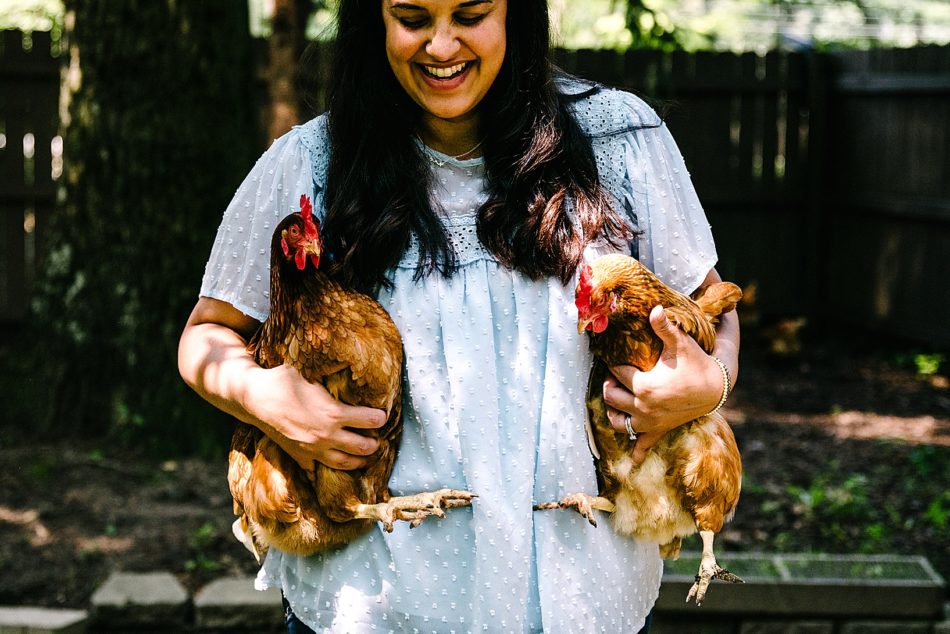 Woman smiling and holding two brown roosters