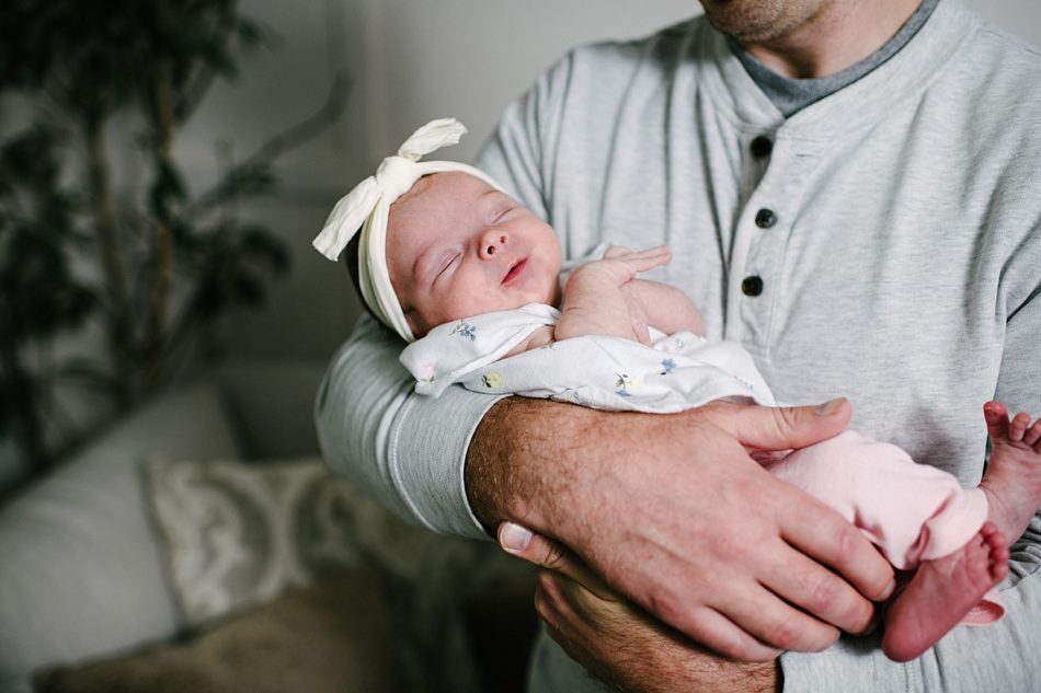 Dad holding Baby Ava while she smiles with her eyes closed wearing a large linen bow