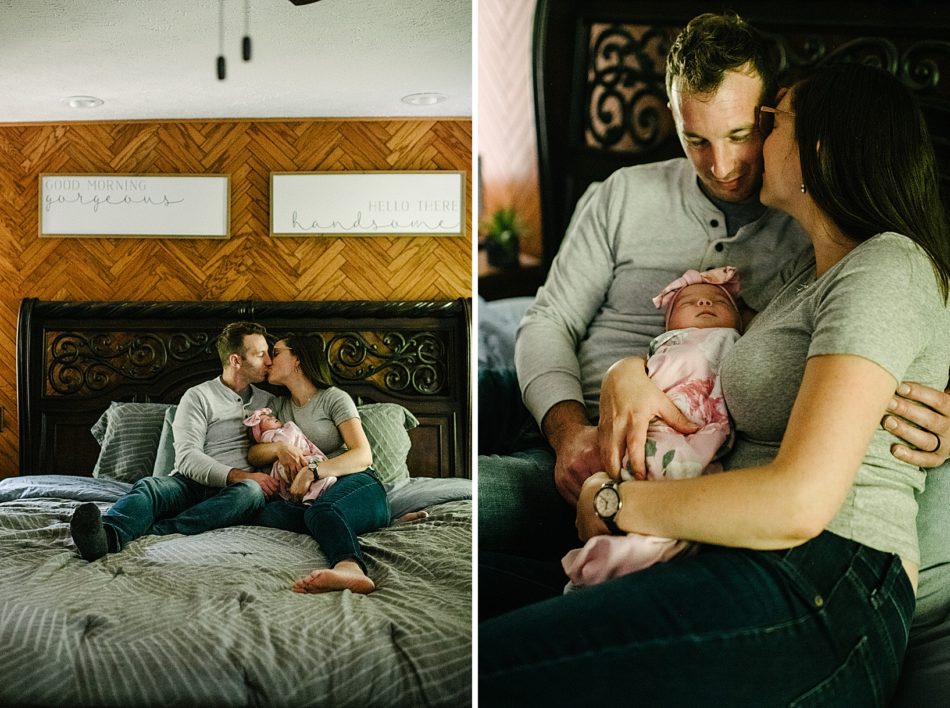 Woman kisses her husband on the cheek as he admires newborn Baby Ava on their bed.