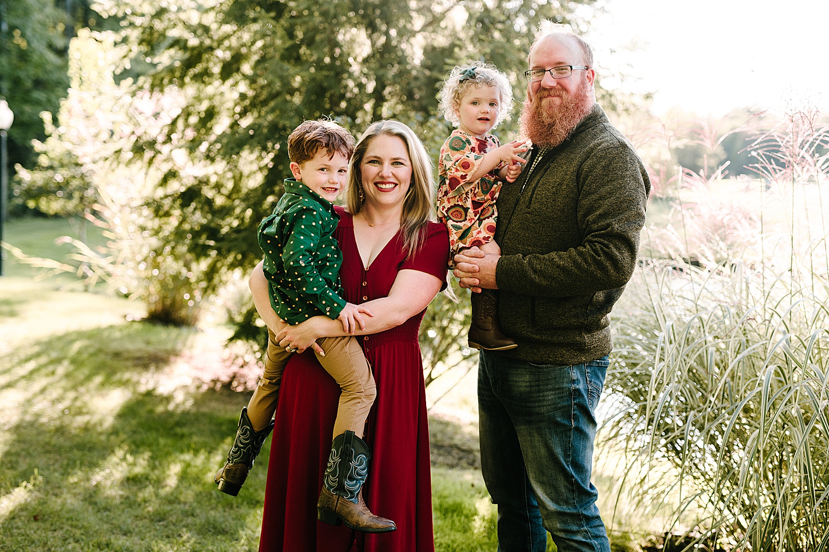 Blonde mom holds her red-headed son and red-bearded dad holds his young daughter wearing cowboy boots and green bow