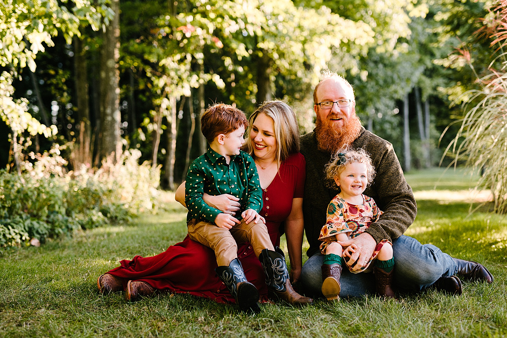 Woman and man sit on the grass with their young son and toddler daughter during fall family session