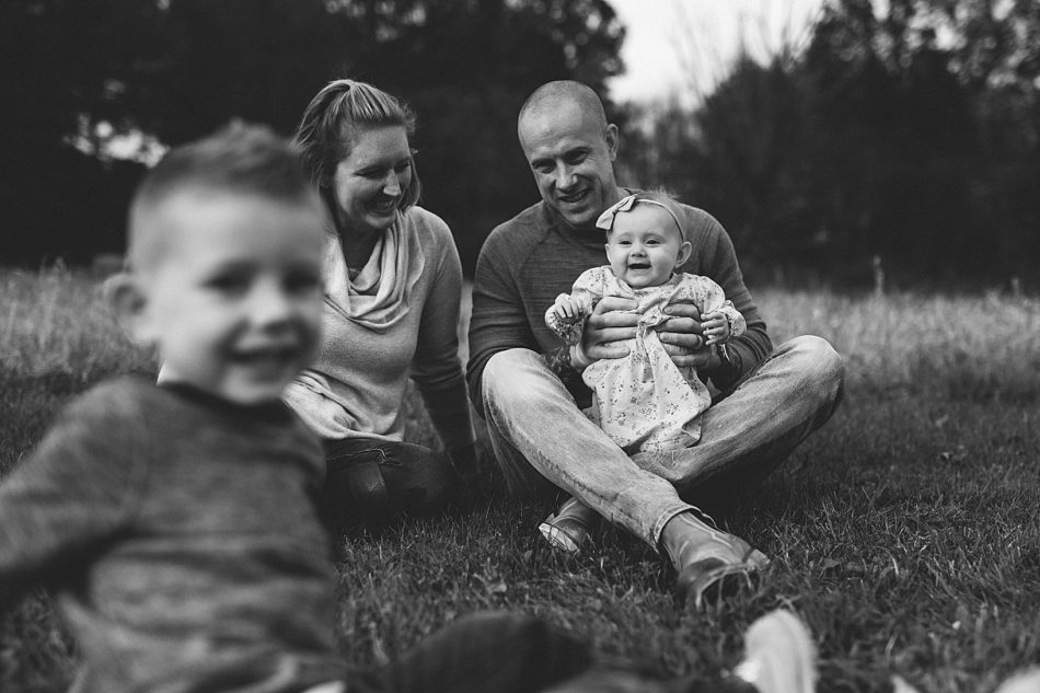 Family of four smiling and laughing while sitting in field in North Jackson, Ohio.